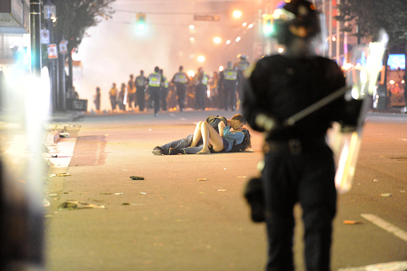 Riot police walk in the street as a couple kisses on June 15, 2011 in Vancouver, Canada. Vancouver broke out in riots after their hockey team the Vancouver Canucks lost in Game Seven of the Stanley Cup Finals. 